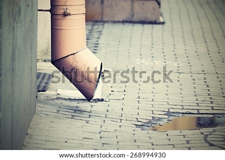 digital photo of a drainpipe and pool on a stone blocks in the old yard or the lane of the old city with effect of retro
