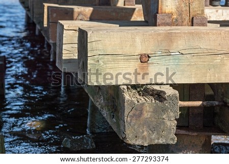 part of an old bridge construction on water from wooden bars and beams