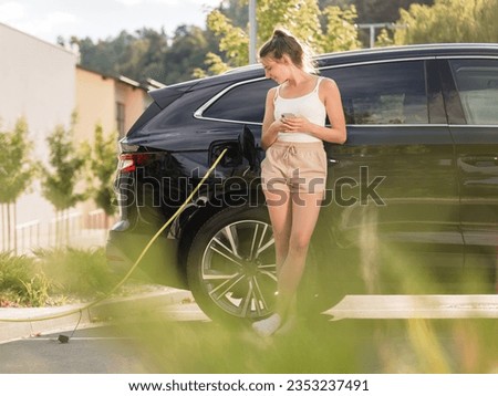 Similar – Image, Stock Photo An elegant woman charging an electric car in urban settings