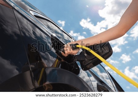 Similar – Image, Stock Photo An elegant woman charging an electric car in urban settings