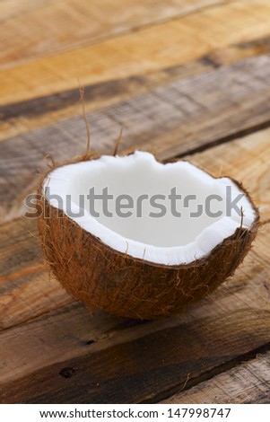 Fresh Coconut. Close up of cracked coconut on wooden table. Shallow depth of field.