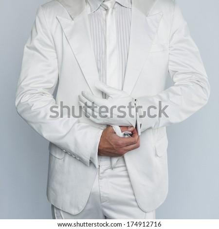 Man in a white suit wearing white gloves.