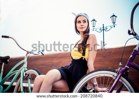 Portrait of a stylish girl hipster posing near two cruiser bicycle