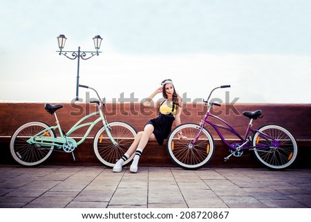 stylish girl hipster posing near two cruiser bicycle