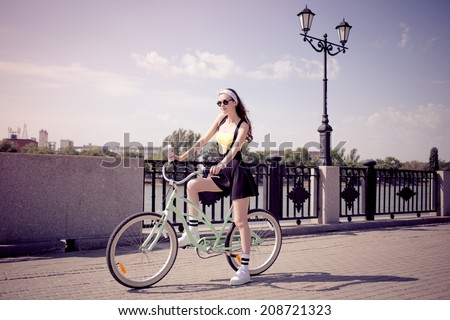 stylish girl hipster riding a cruiser bicycle with a disposable coffee
