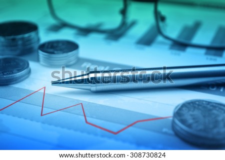 Pen, glasses and coin on financial chart and graph, accounting background