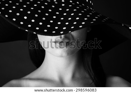 Fashion portrait of a woman with lock hair and  black and white dots hat and pout lips