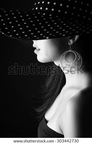 Side face of young woman in black hat with dots and with stylish earring
