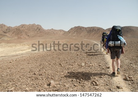 NEGEV DESERT, ISRAEL - APRIL 14: Three hikers from Europe walking near natural crater Makhtesh Ramon in Negev Desert on April 14, 2013 in Negev Desert, Israel.