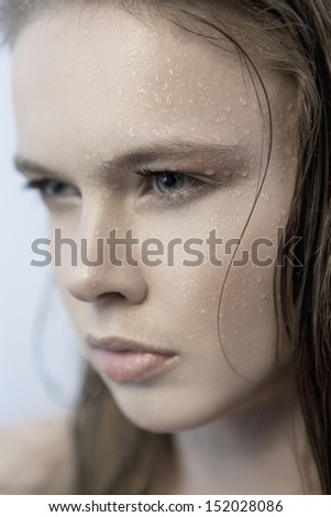 Close-up portrait of young beautiful woman with drops of water on her face looking away
