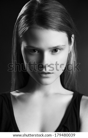 Close up portrait of young woman with natural make up and long hair, looking at camera. Black and White photo