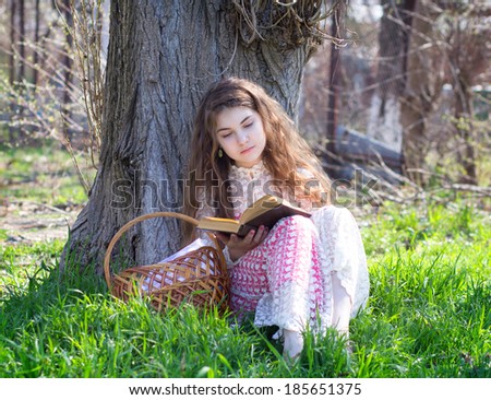 girl reading a book under a tree in nature