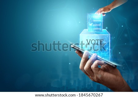 Online voting, Hand with a hologram ballot and a box for Internet voting in a mobile phone on a blue background. Mixed environment, e-voting technology concept