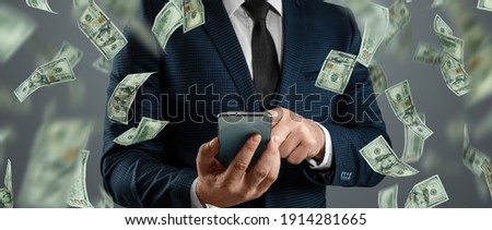 Online sports betting. A man in a suit is holding a smartphone and dollars are falling from the sky. Creative background, gambling