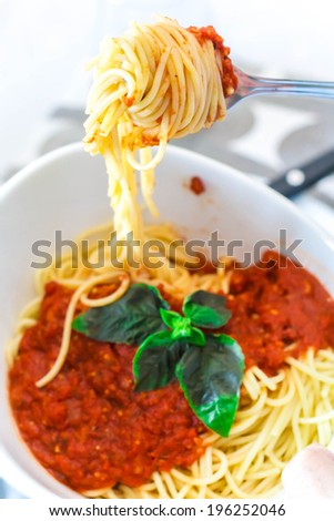 Bowl of spaghetti with marinara sauce and basil leaves on top