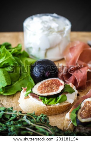Finger food with figs, tomatoes and prosciutto, arugula, goat cheese
