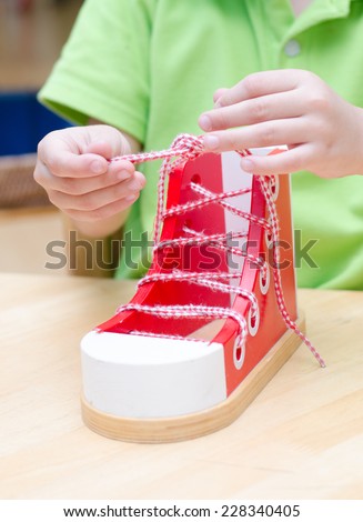 Little boy learn how to tie shoes wooden