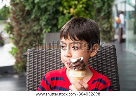 Little boy eating ice cream at the shop outdoor summer time