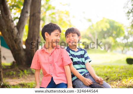 Little sibling boy sitting together in the park