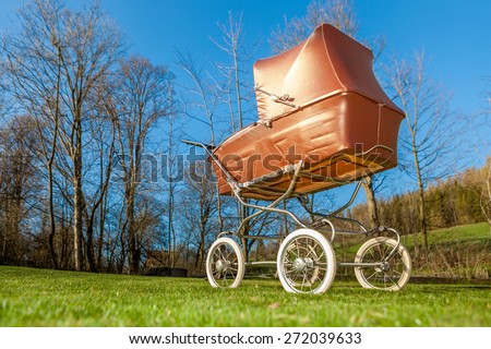 Low view on retro style stroller baby carriage outdoors in nature on sunny day