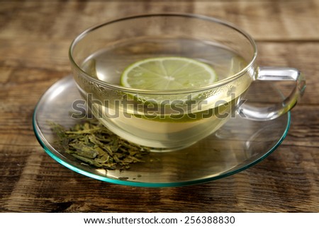 The cup of green tea with tea leaves and lemon