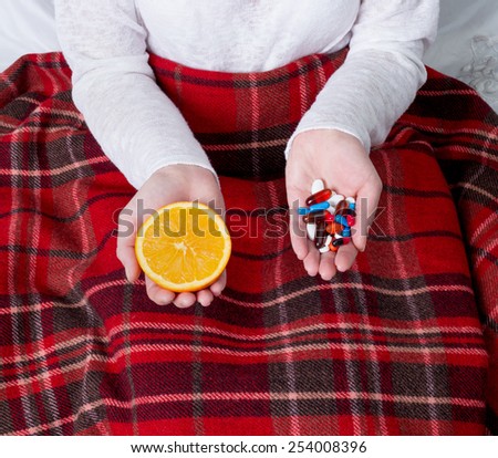 pills and orange in the hands of a sick person