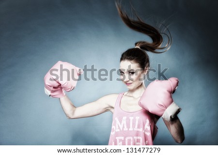 Female boxer model wearing big fun pink gloves playing sports boxing hair motion, blue background