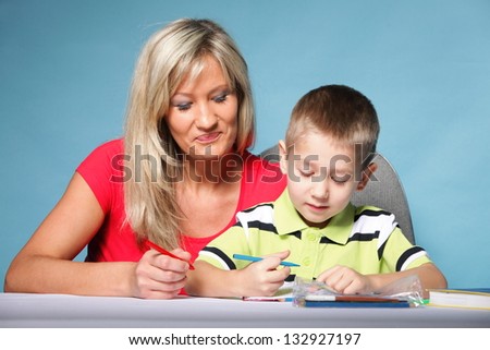 mother and son drawing together, mom helping with homework blue background