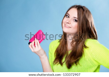 Happy girl with mobile phone in pink cover blue background