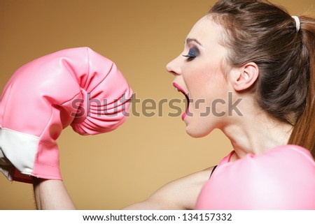 Female boxer model wearing big fun pink gloves playing sports boxing studio shot, blue background