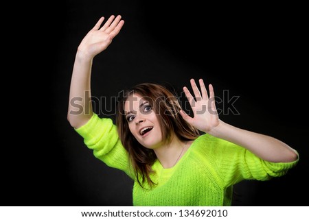 Beautiful happy laughing girl in bright vivid colour sweater hold hands up on black background