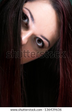 Woman make-up covers the part of face by long dark straight hair white background