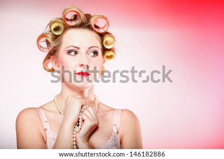 Sexy woman preparing to party, girl in underwear curlers in hair with beads pink background