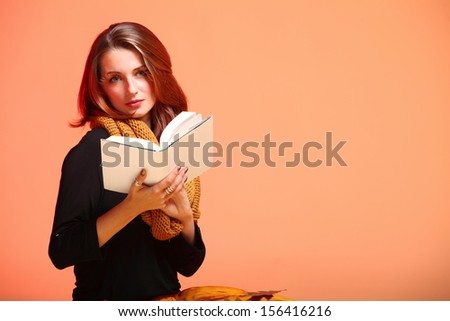 Fall. Fashion woman in autumn color student girl with book long false orange eye-lashes