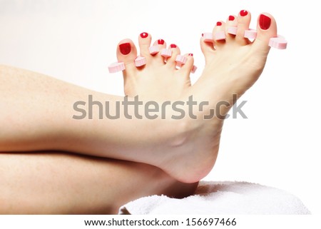 foot pedicure applying woman\'s feet with red toenails in toe separators white background