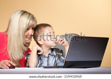 mother with son together looking on the laptop orange background