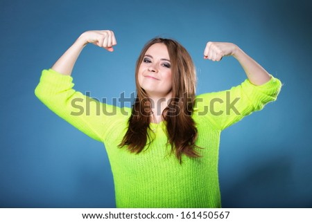 woman long hair clenching fists shows her muscles blue background strength and power concept