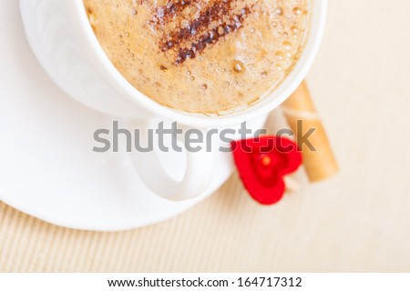 White cup of hot beverage drink coffee cappuccino latte with froth, sweet waffle roll stick with cream and red heart love symbol. Valentine\'s day. Studio shot.