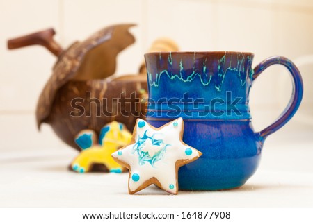 Blue mug of hot beverage drink tea or coffee and homemade gingerbread cake star with icing and decoration. Christmas and holiday handmade concept.