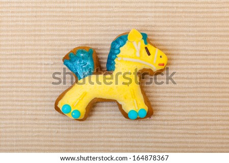 Homemade gingerbread cake pony with icing and blue yellow decoration on brown. Christmas. Holiday handmade concept.