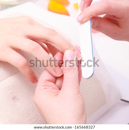 Beautician with file filing nails female client. Woman spa beauty salon. Manicure