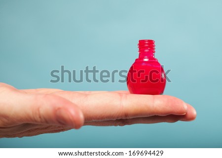 Pedicure manicure red nail polish bottle on female hand blue background