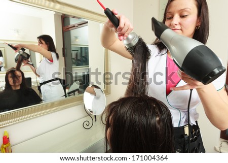 Hairstylist with brush and dryer. hairdresser drying hair of female client. Woman in hairdressing beauty salon.