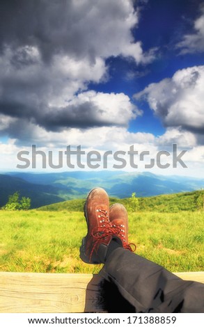 Hiking shoes boots. Male hiker enjoying view relaxing looking at nature in hills landscape mountains. Dark sky with clouds Bieszczady Poland