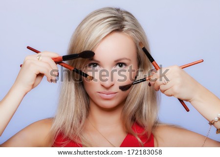 Cosmetic beauty procedures and makeover concept. Attractive woman red dress holds makeup professional brushes near face. Make-up applying with accessories tools. Blue background