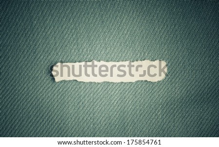 Piece scrap of white torn or ripped paper banner, blank copy space for text message on blue fabric textile material background