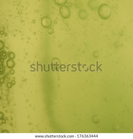 Green abstract blurred liquid background with soap bubbles. Square format
