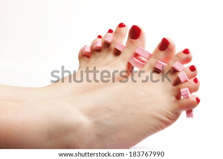 foot pedicure applying woman\'s feet with red toenails in toe separators white background