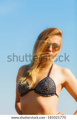 Vacation. Sexy girl in bikini standing alone on the empty beach. Young woman relaxing on the sea coast. Summertime.