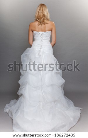 Wedding day. beautiful blonde bride long white dress in full length back view studio shot on gray background